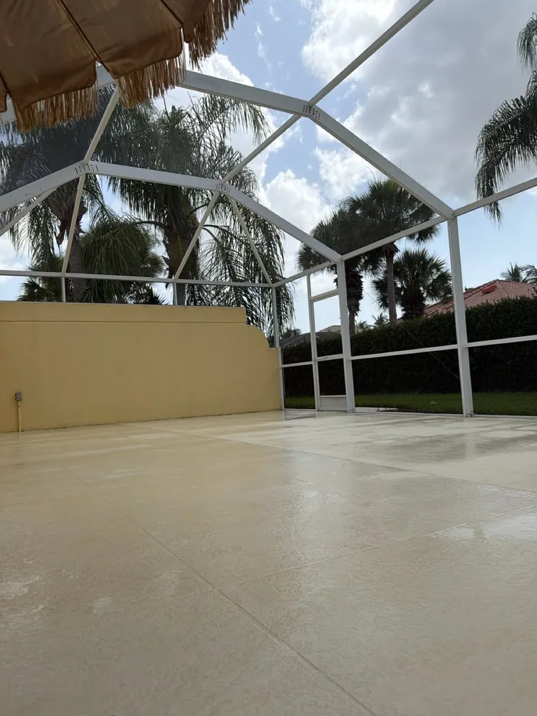 Light patio floor and white screen enclosure at a Naples pressure-washing project