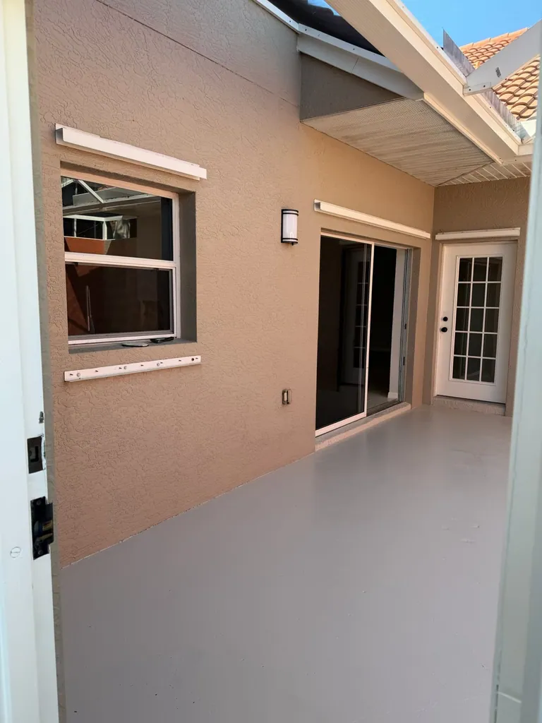 Covered lanai with gray floor and stucco walls at a Naples pressure-washing project