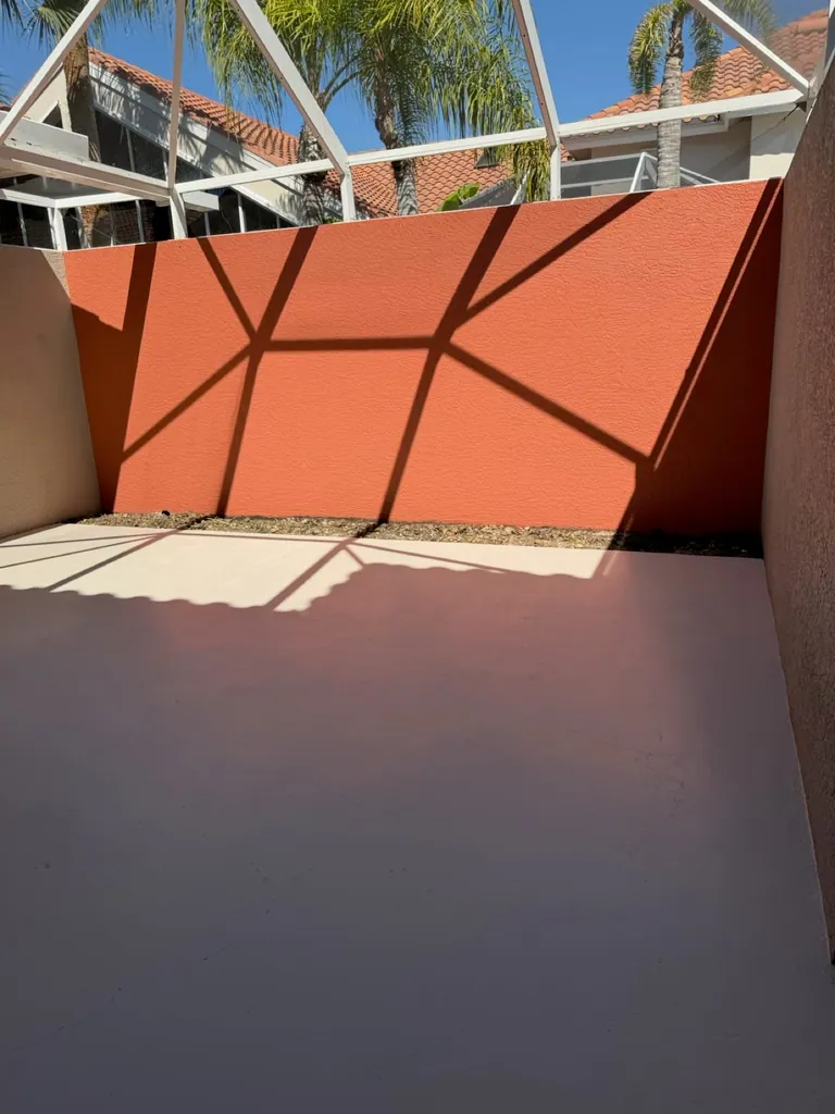 Outdoor patio with coral wall and white enclosure at a Naples pressure-washing project